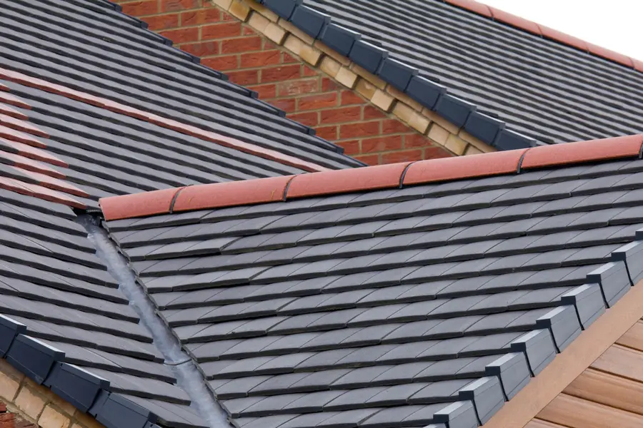 Dark tiled roof with a red ridge, lead valley and brick gable, seen from above